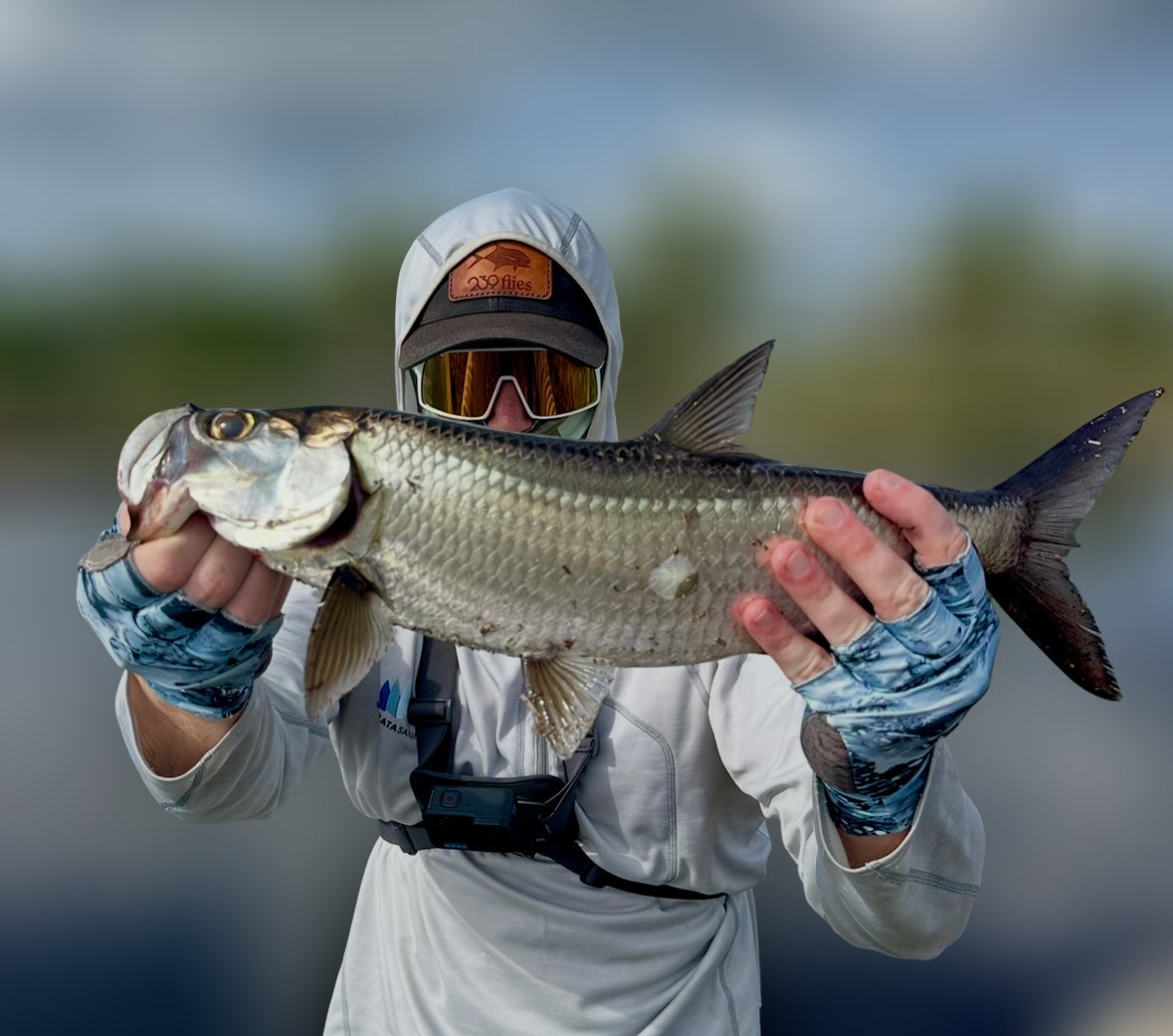 Angler holding large tarpon fish, showcasing catch with biodegradable fishing bait